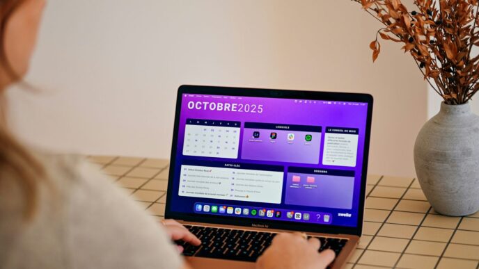 Woman using laptop with october 2025 calendar displayed.