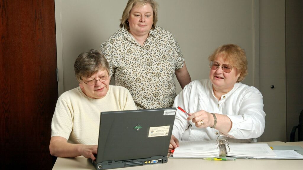 woman in white cardigan sitting beside woman in black and white floral shirt