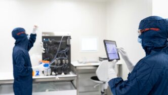 a couple of people in blue protective gear in front of a computer