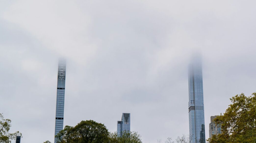 Skyscrapers emerge from a thick, foggy sky.