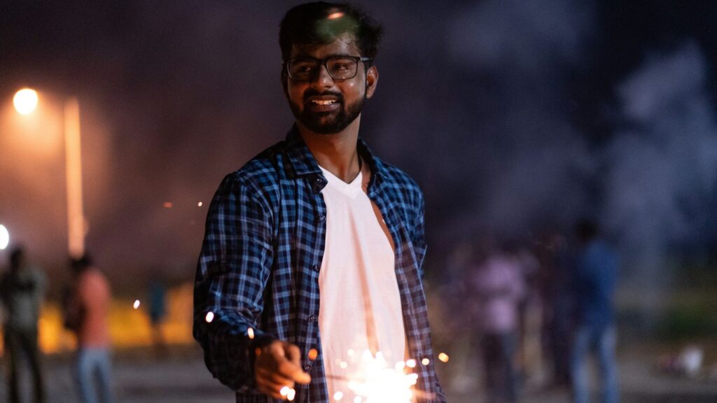 man holding lightened sparkler outdoor at night