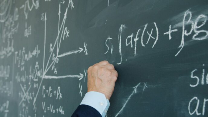 Hand writing mathematical formulas on a chalkboard.