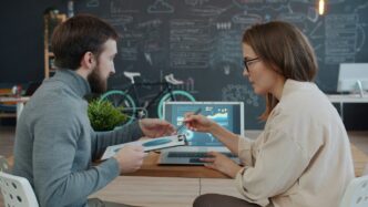 Two colleagues reviewing data on a laptop.