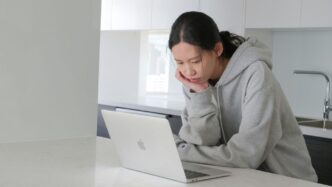 man in gray hoodie sitting beside white table
