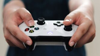 person holding white and black xbox one game controller