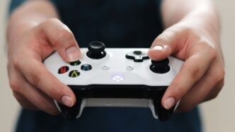 person holding white and black xbox one game controller
