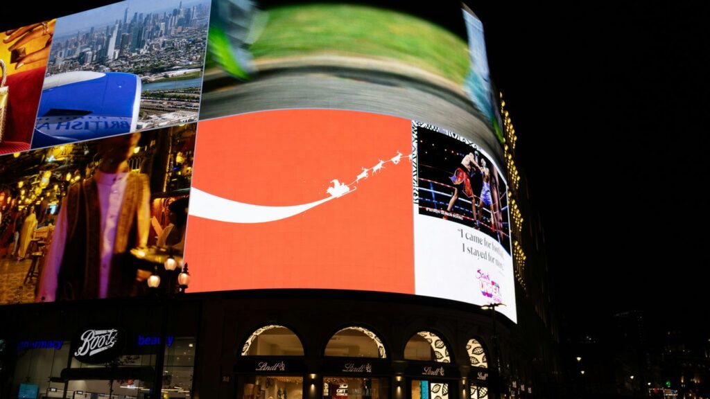Bright billboards illuminate a city street at night.