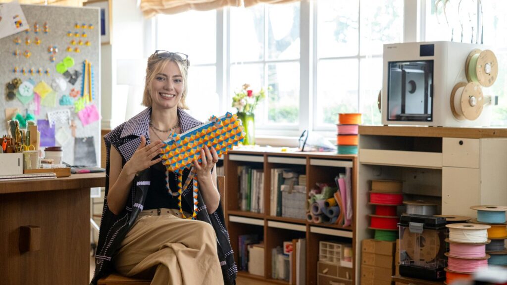 Woman holding colorful beaded necklace in workshop