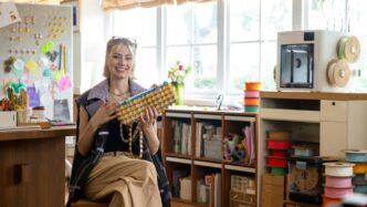 Woman holding colorful beaded necklace in workshop