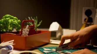 person cutting paper beside orange tray