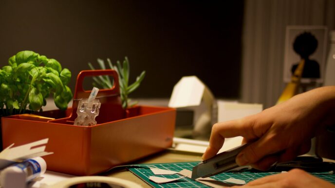 person cutting paper beside orange tray