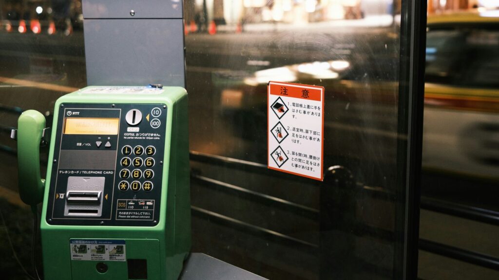 a green pay phone sitting next to a parking meter