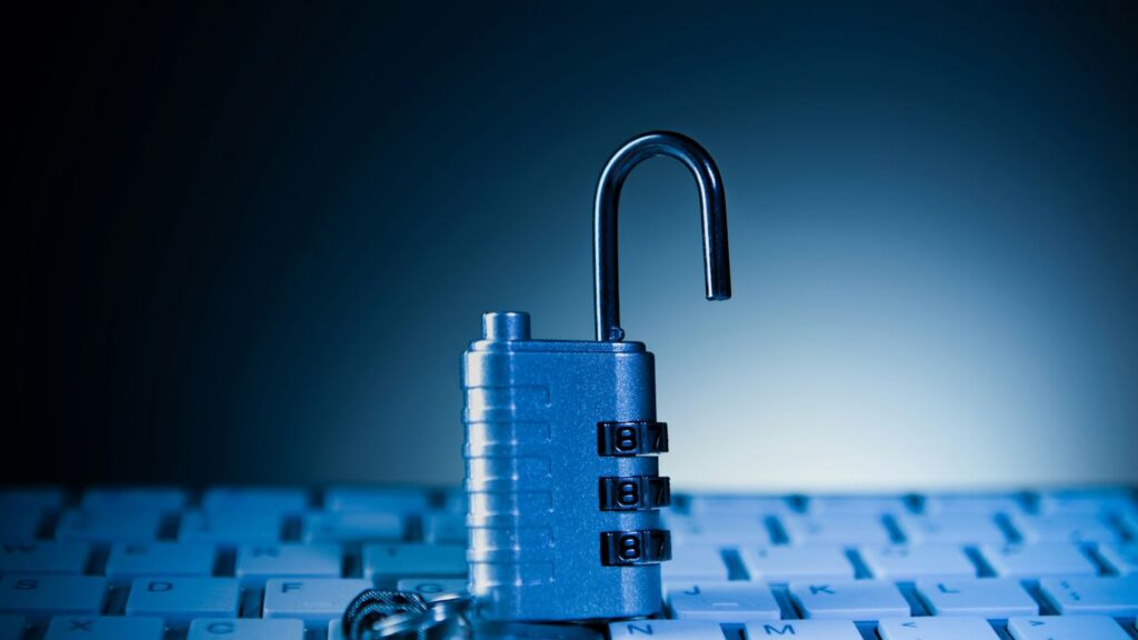 An unlocked padlock rests on a computer keyboard.