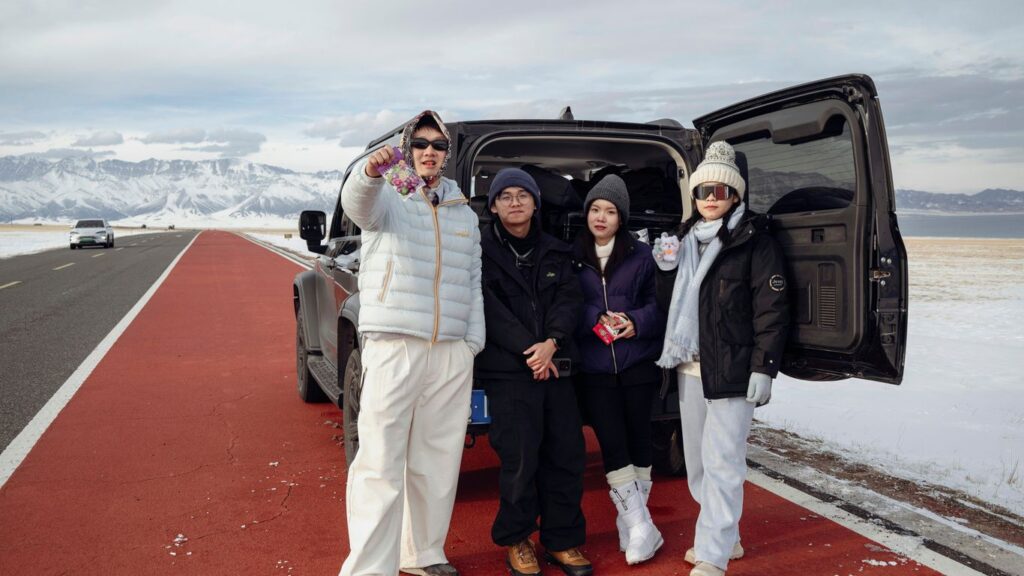 Four people standing by a car in a snowy landscape.