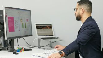 a man sitting at a desk with a laptop and a computer