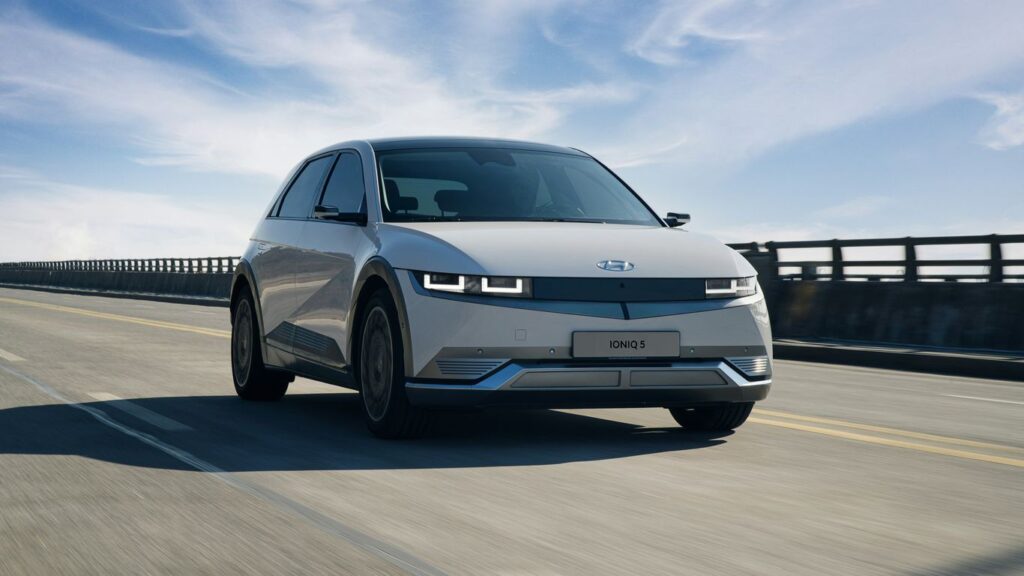 a white car driving down a highway next to a bridge