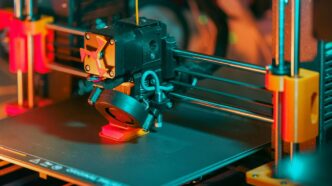 3D printer creating a red object with yellow filament.