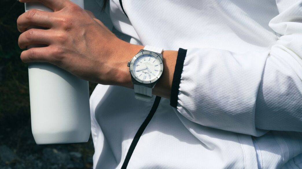 a person with a watch on their wrist holding a white bottle