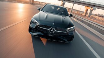 Black mercedes c-class driving on highway at sunset