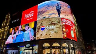 Brightly lit billboards on a building at night.