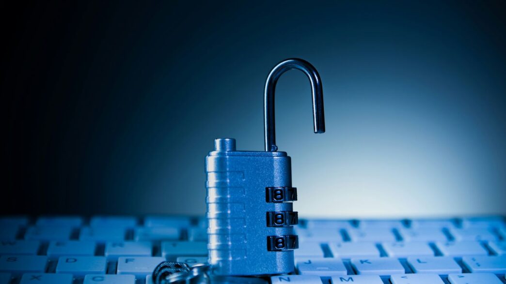 An unlocked padlock rests on a computer keyboard.