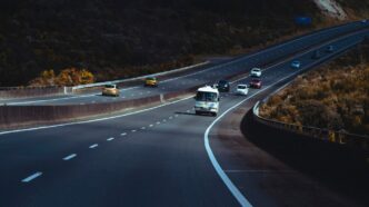 a highway filled with lots of traffic next to a hillside
