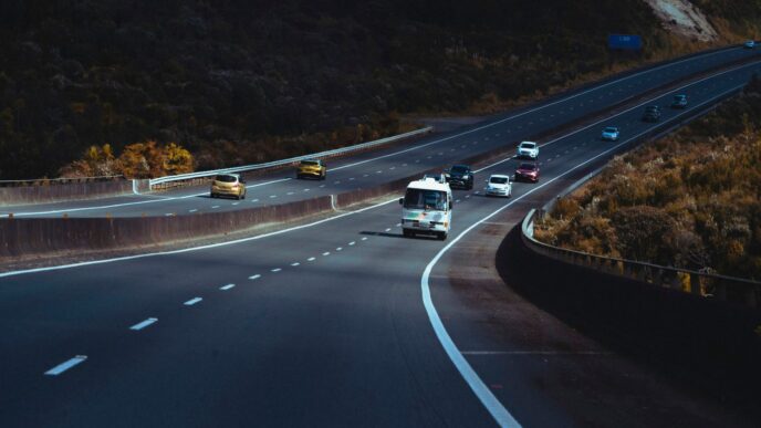 a highway filled with lots of traffic next to a hillside