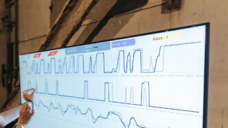 a woman points to a chart on a large screen