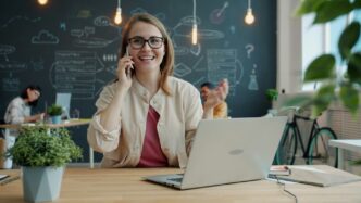 Smiling woman talking on phone in modern office.