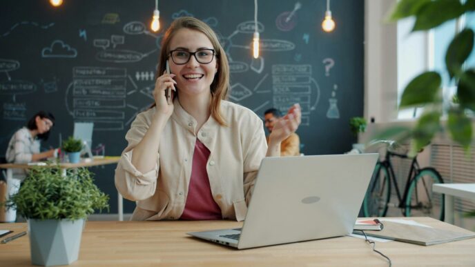Smiling woman talking on phone in modern office.