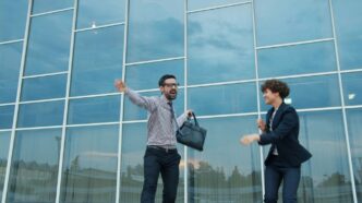 Two business people celebrating outside modern office building