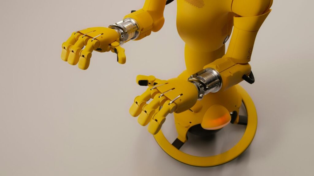 Yellow robot with articulated hands on a white background
