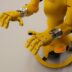 Yellow robot with articulated hands on a white background