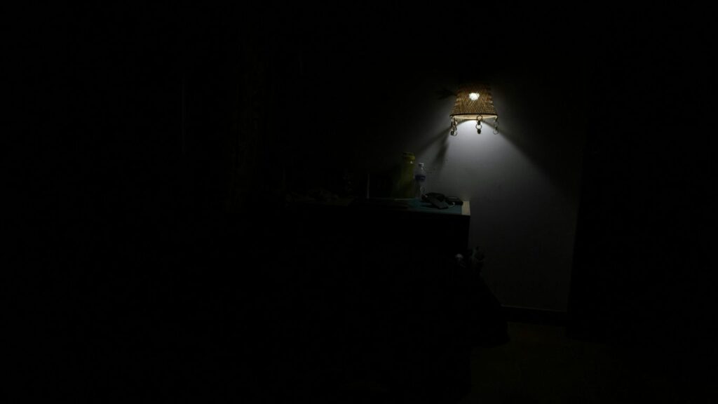 a dark room with a lamp on the wall