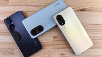 Three smartphones in different colors on a wooden surface