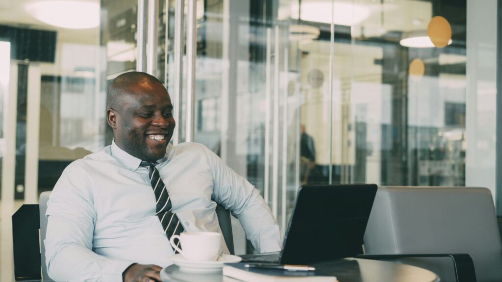Man laughing while working on laptop with coffee