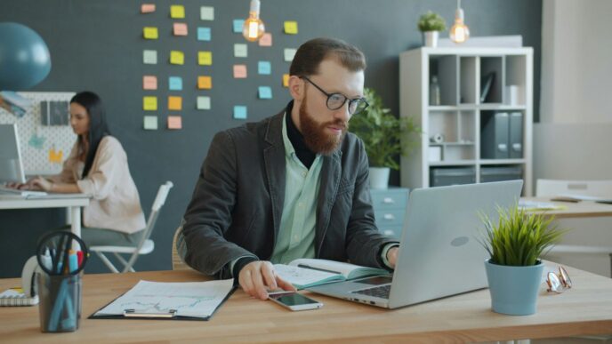Man working on laptop in modern office with sticky notes