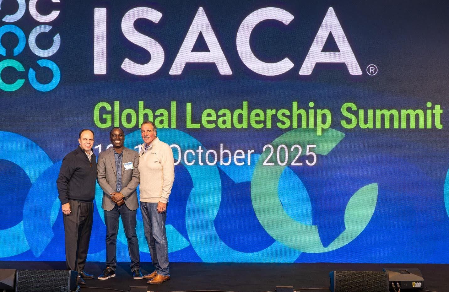 ISACA Calgary President, Joseph Edivri (M) on stage picture with ISACA Global Chair, John De Santis (R)  and ISACA CEO, Erik Prusch (L) at the Global Leadership Summit in Hammersmith, London, UK