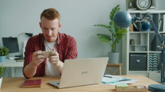 Man playing a video game on his phone at desk.