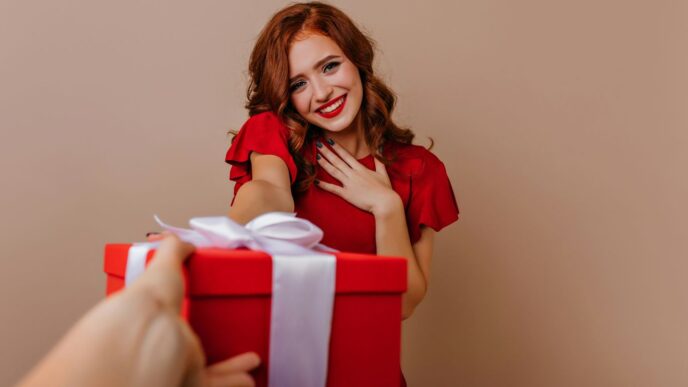 a woman holding a red gift box with a white ribbon
