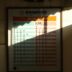 A timetable with sunlight casting a shadow.