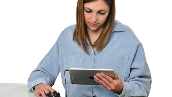 a woman sitting at a table looking at a tablet