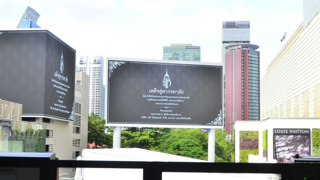 Billboard with thai script and ornate border in city.