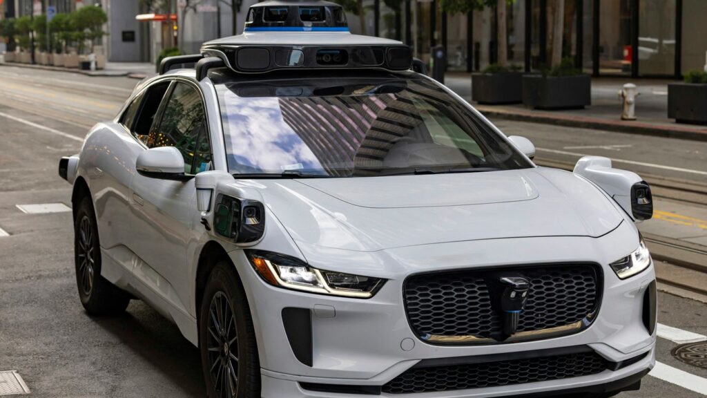 A white self-driving car on a city street.