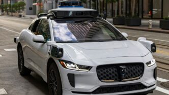 A white self-driving car on a city street.