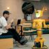 Man in cafe interacts with a yellow robot.