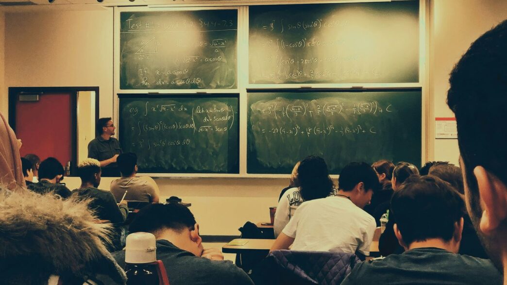 student sitting on chairs in front of chalkboard