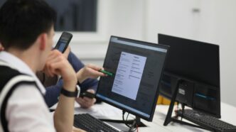 A group of people sitting at a table with computers