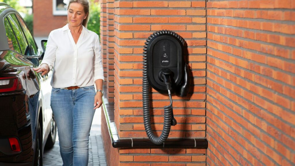 Woman plugging electric car into wall charger