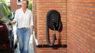 Woman plugging electric car into wall charger